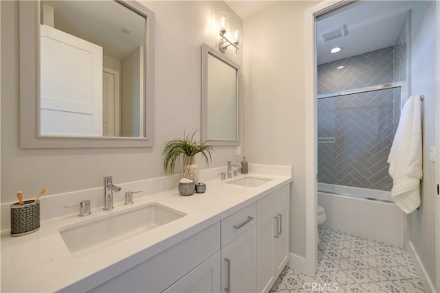 full bathroom with double vanity, combined bath / shower with glass door, a sink, and toilet