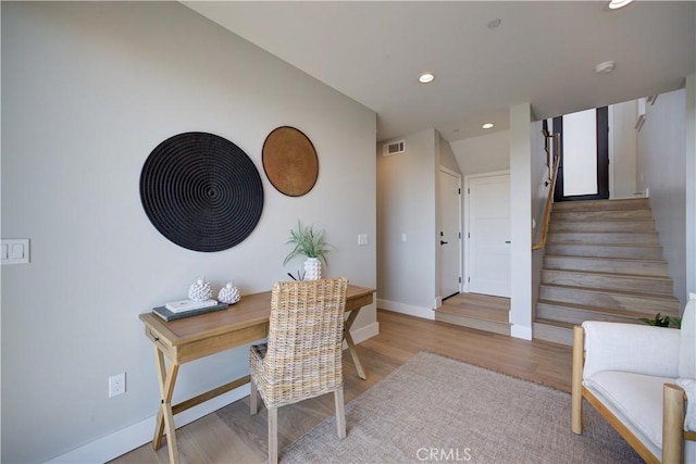 office area with light wood-style floors, recessed lighting, visible vents, and baseboards