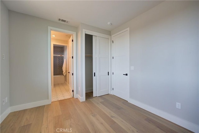 unfurnished bedroom with light wood-style flooring, ensuite bath, visible vents, and baseboards