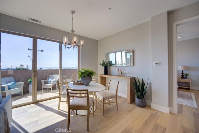 dining space featuring french doors, light wood finished floors, visible vents, an inviting chandelier, and baseboards