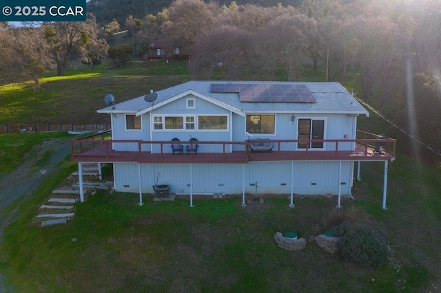 back of house with solar panels, central air condition unit, a yard, and a wooden deck