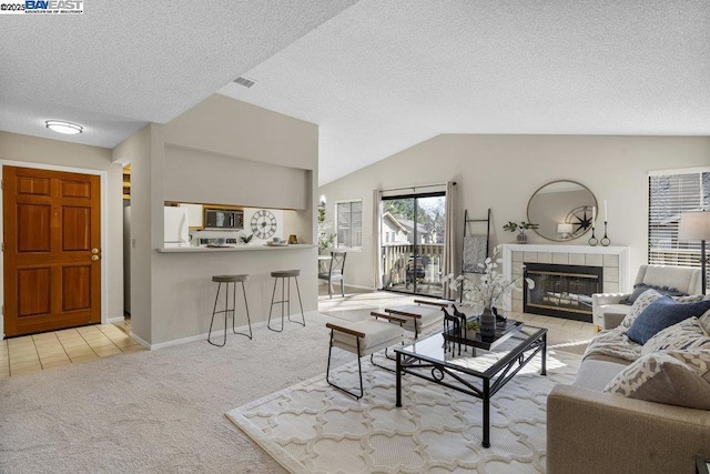 living room featuring a fireplace, a textured ceiling, vaulted ceiling, and light carpet