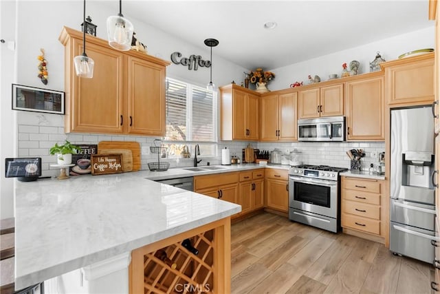 kitchen with sink, decorative light fixtures, kitchen peninsula, and appliances with stainless steel finishes