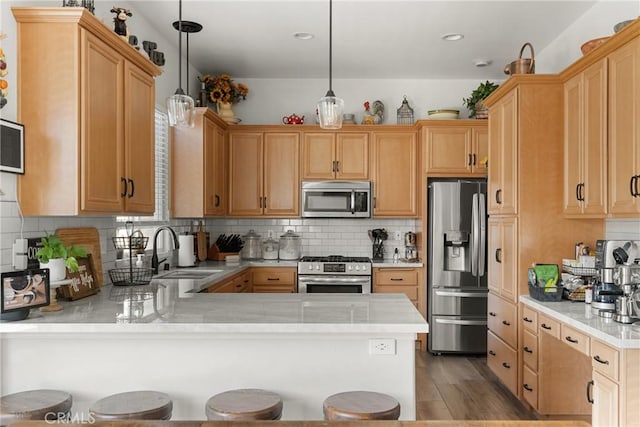 kitchen with stainless steel appliances, hanging light fixtures, kitchen peninsula, sink, and backsplash