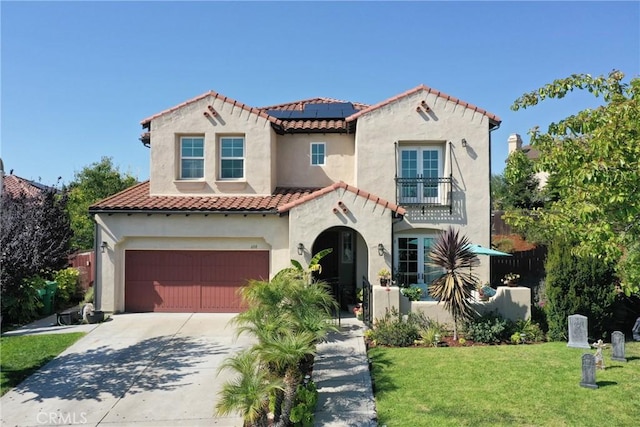 mediterranean / spanish home with solar panels, a balcony, a front lawn, and a garage