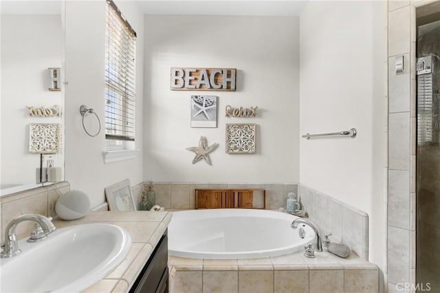 bathroom featuring vanity and tiled bath