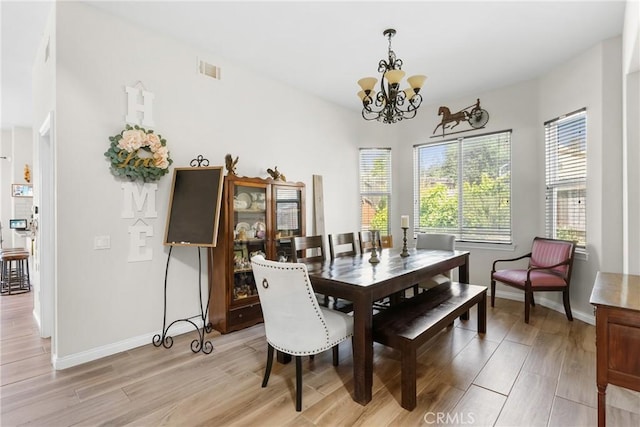 dining space featuring light wood-type flooring and an inviting chandelier