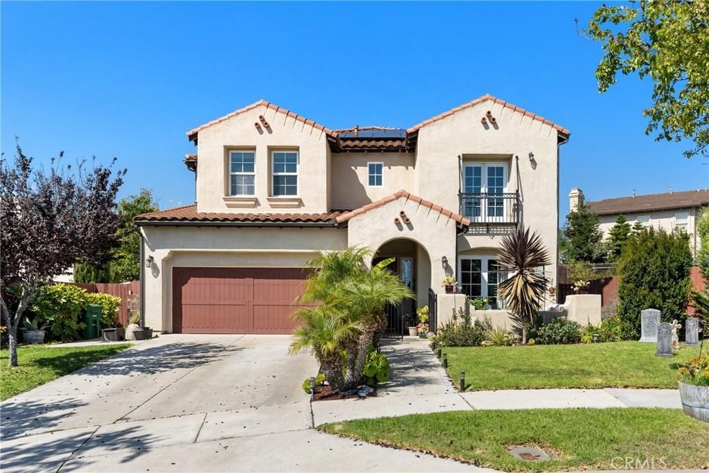 mediterranean / spanish-style house with a balcony, a front lawn, and a garage