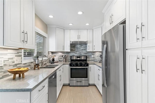 kitchen with stainless steel appliances, white cabinetry, sink, and light stone countertops