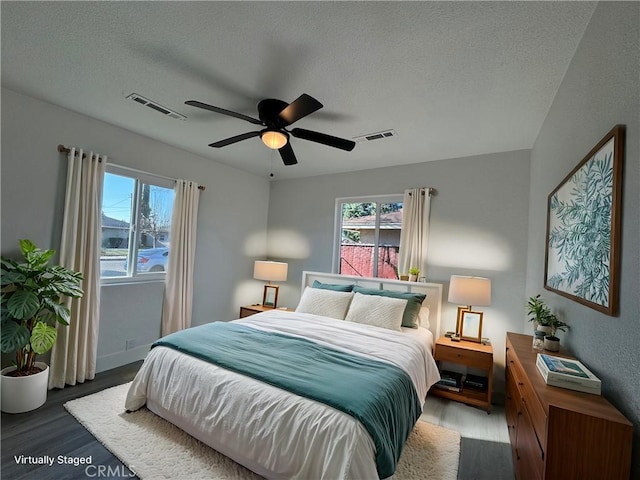 bedroom with a textured ceiling, ceiling fan, and hardwood / wood-style floors