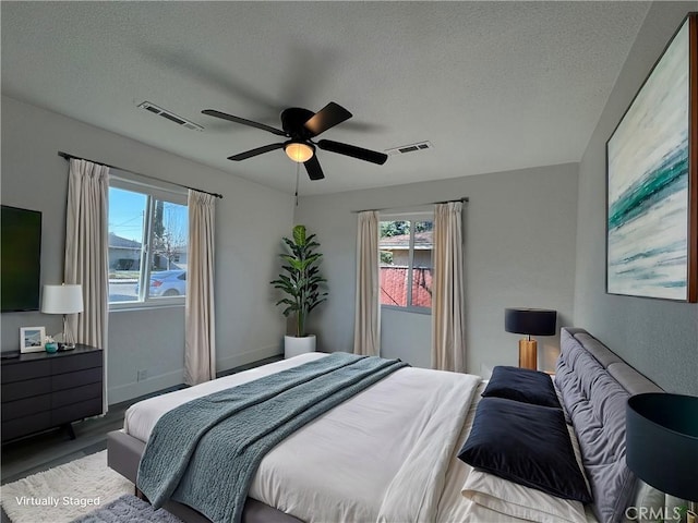 bedroom featuring hardwood / wood-style floors, a textured ceiling, and ceiling fan