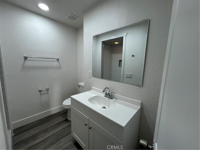 bathroom with toilet, hardwood / wood-style flooring, and vanity