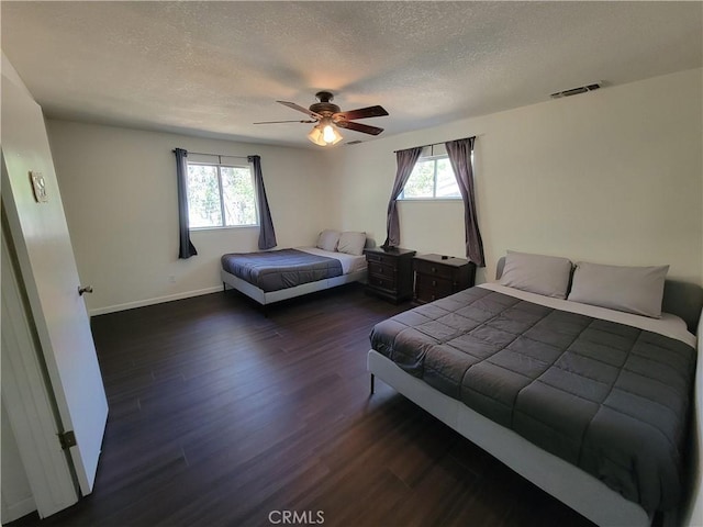 bedroom with visible vents, a textured ceiling, multiple windows, and wood finished floors