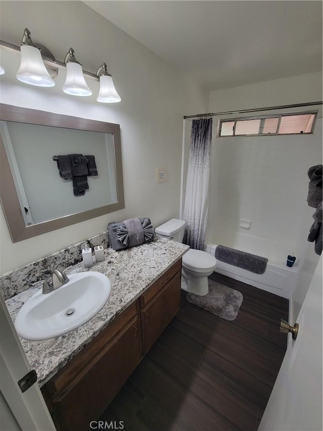 bathroom featuring shower / bathtub combination with curtain, vanity, toilet, and wood finished floors