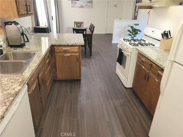 kitchen with white appliances, wood tiled floor, under cabinet range hood, and brown cabinetry