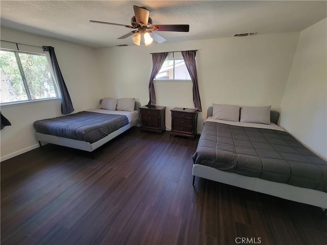 bedroom with baseboards, visible vents, dark wood finished floors, a ceiling fan, and a textured ceiling