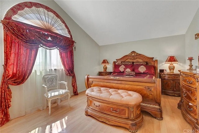 bedroom featuring light wood finished floors and vaulted ceiling