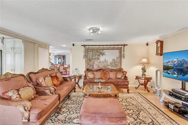 living area with ornamental molding, light wood-type flooring, and a textured ceiling