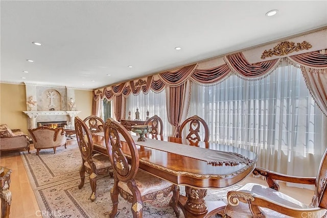 dining room with a lit fireplace, light wood-style flooring, and recessed lighting