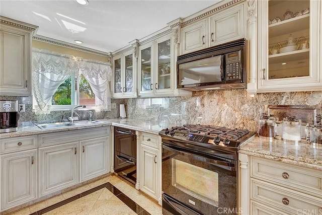 kitchen featuring black appliances, cream cabinets, a sink, and decorative backsplash