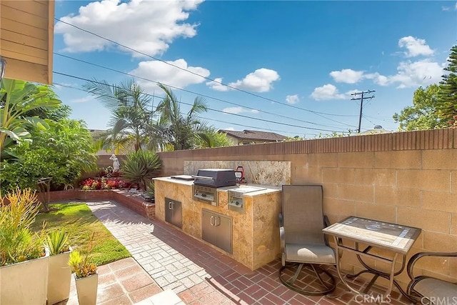 view of patio featuring exterior kitchen, a fenced backyard, and area for grilling