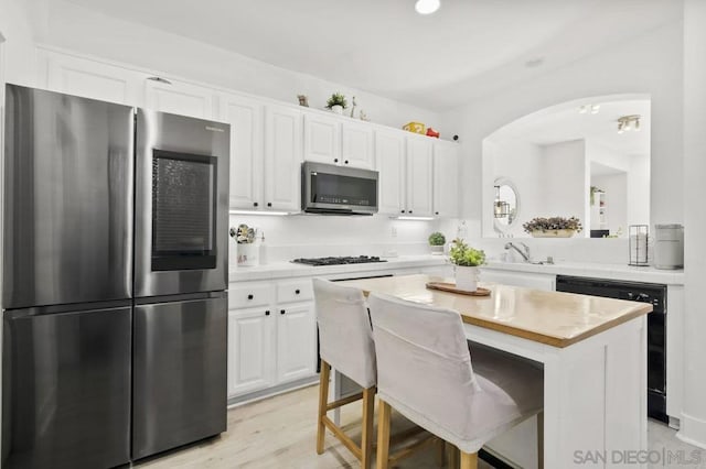 kitchen with stainless steel appliances, sink, white cabinets, a center island, and a breakfast bar area