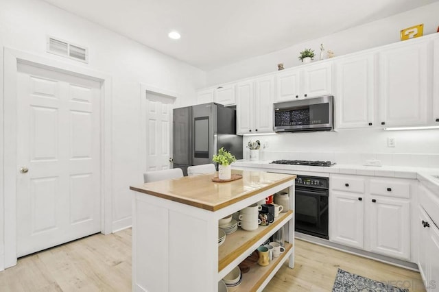 kitchen featuring light hardwood / wood-style flooring, stainless steel appliances, white cabinetry, and a kitchen island