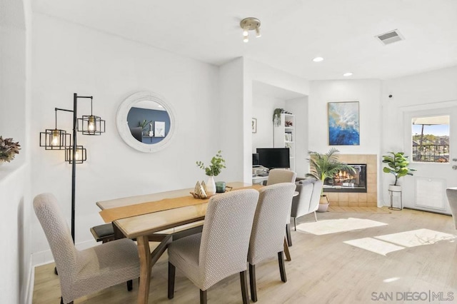 dining space featuring a tiled fireplace and light hardwood / wood-style floors