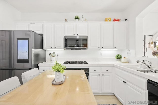 kitchen featuring black appliances, white cabinetry, and sink