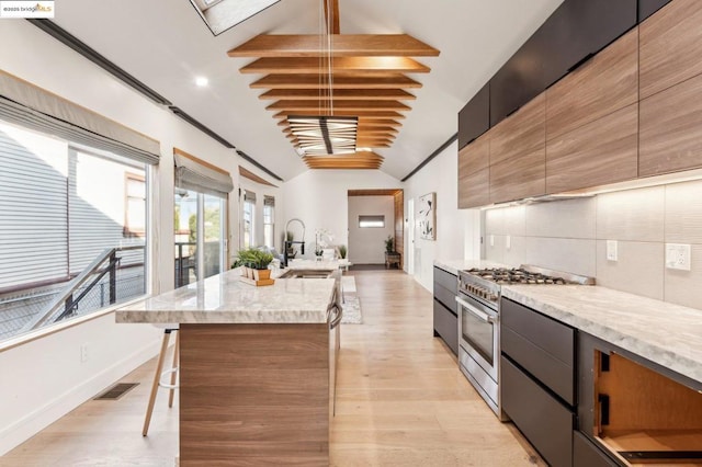 kitchen featuring high end range, vaulted ceiling with beams, a kitchen island, decorative backsplash, and sink