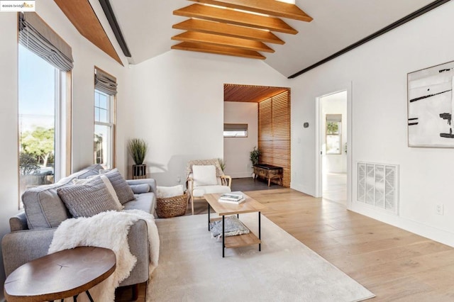 living room featuring light hardwood / wood-style floors and vaulted ceiling with beams