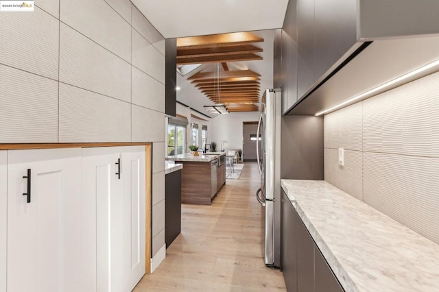 kitchen with beam ceiling, stainless steel fridge, and light hardwood / wood-style flooring