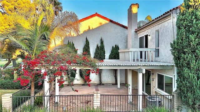 rear view of property featuring a balcony and a patio area