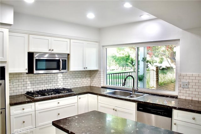 kitchen with stainless steel appliances, white cabinets, tasteful backsplash, and sink