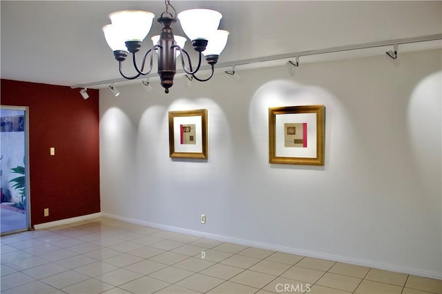 tiled spare room with a chandelier and rail lighting