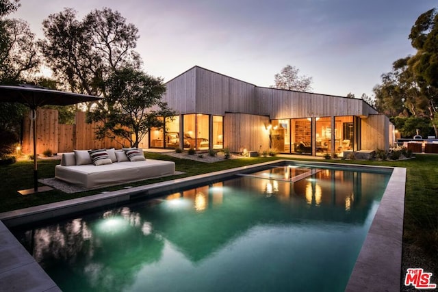 pool at dusk featuring outdoor lounge area