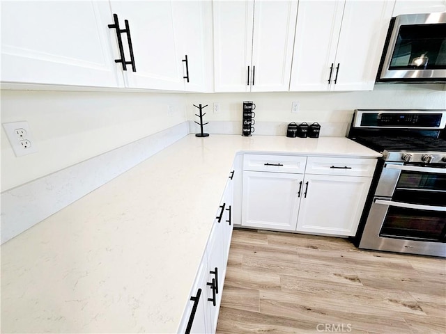 kitchen with white cabinets, light hardwood / wood-style flooring, and appliances with stainless steel finishes