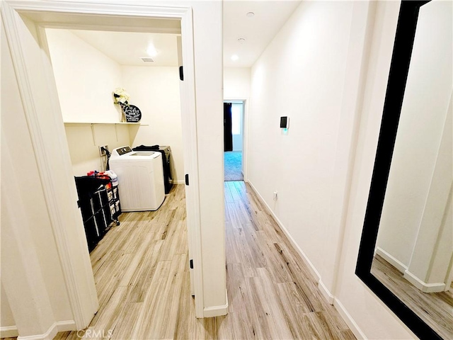 hall with independent washer and dryer and light hardwood / wood-style flooring