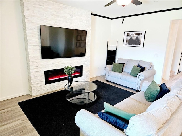 living room featuring hardwood / wood-style floors, ceiling fan, and a stone fireplace