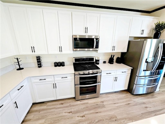 kitchen with white cabinets, appliances with stainless steel finishes, and light hardwood / wood-style floors