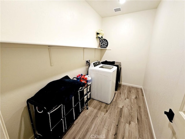 laundry room featuring wood-type flooring and separate washer and dryer