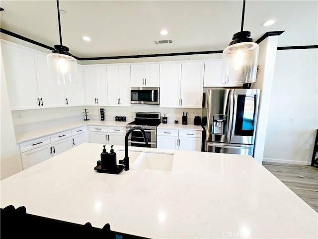 kitchen with stainless steel appliances, sink, decorative light fixtures, white cabinetry, and light wood-type flooring