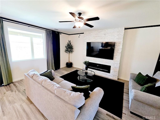 living room with a fireplace, ceiling fan, and light hardwood / wood-style flooring