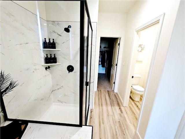 bathroom featuring toilet, tiled shower, and hardwood / wood-style flooring