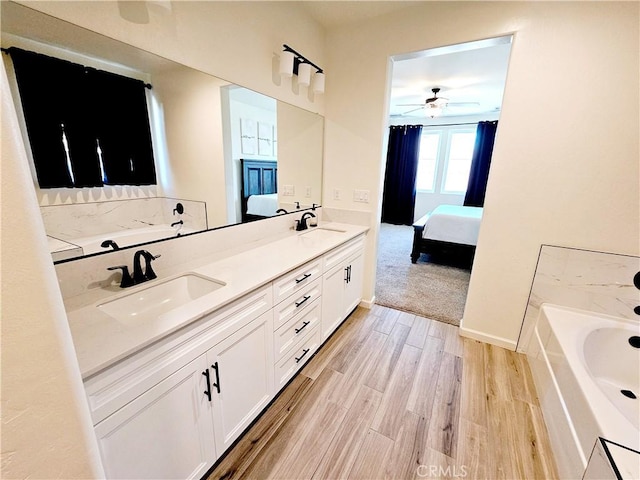 bathroom with vanity, ceiling fan, hardwood / wood-style flooring, and a bathing tub