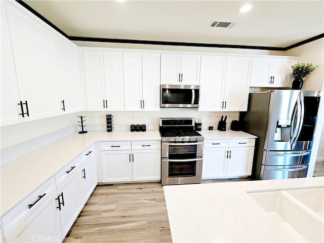 kitchen featuring sink, white cabinetry, light hardwood / wood-style floors, and appliances with stainless steel finishes