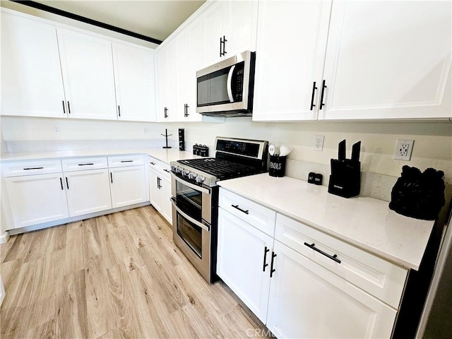 kitchen featuring appliances with stainless steel finishes, white cabinetry, and light wood-type flooring