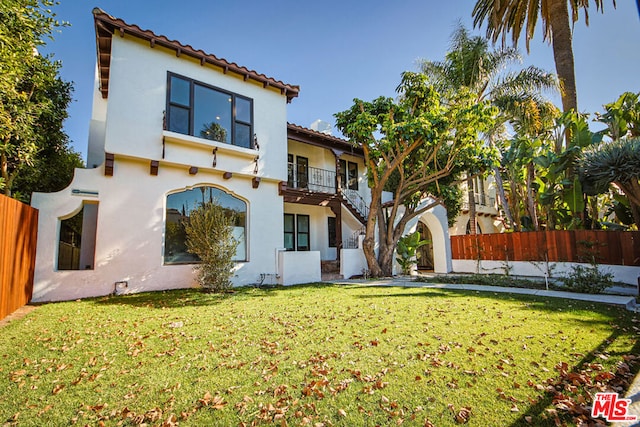 rear view of property with a balcony and a yard