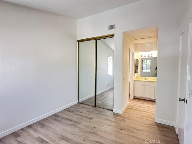 unfurnished bedroom with light wood-style floors, visible vents, baseboards, and a closet