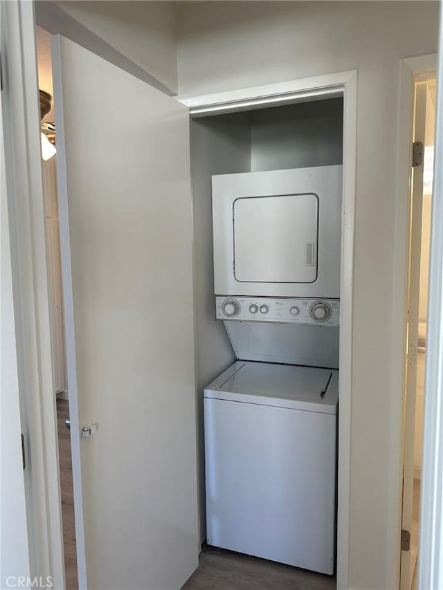 washroom featuring wood finished floors, laundry area, and stacked washing maching and dryer